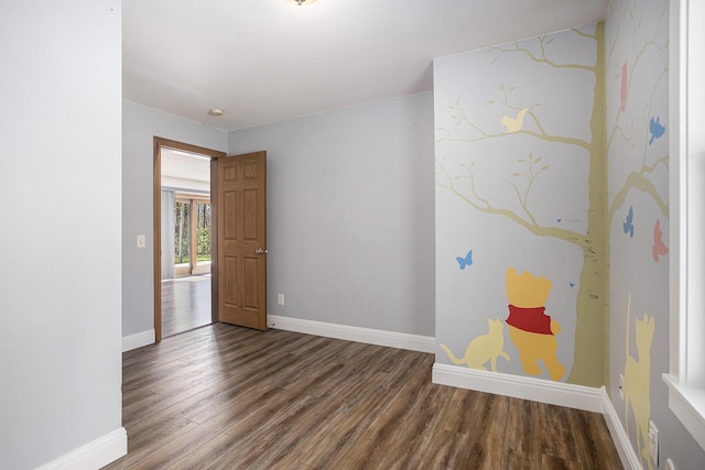 spare room with baseboards and wood finished floors
