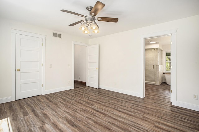 unfurnished bedroom with connected bathroom, baseboards, visible vents, and wood finished floors