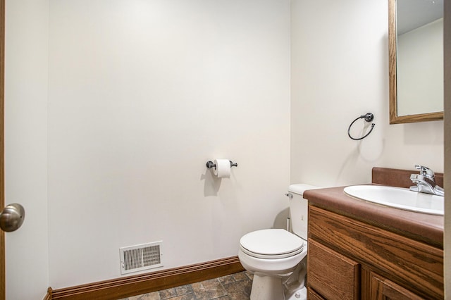 bathroom featuring stone finish floor, visible vents, baseboards, vanity, and toilet