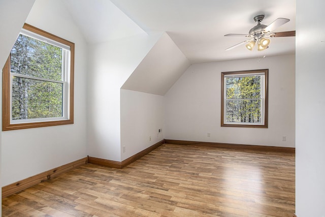bonus room with light wood-style floors, a healthy amount of sunlight, and vaulted ceiling