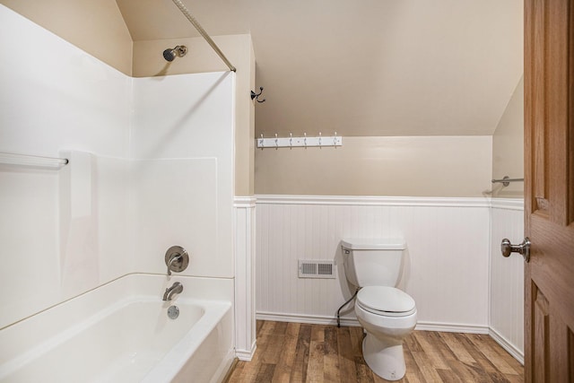 bathroom with a wainscoted wall, wood finished floors, and shower / washtub combination