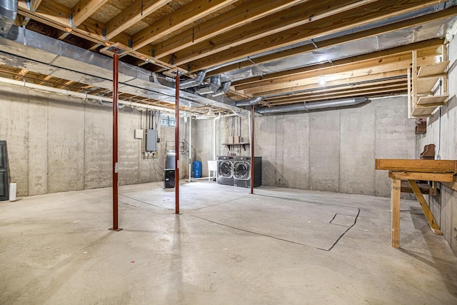 unfinished below grade area featuring electric panel and washing machine and clothes dryer