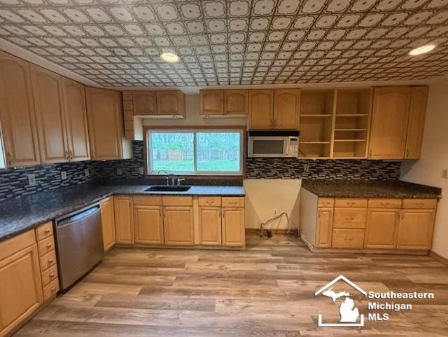 kitchen featuring light brown cabinets, light wood-style floors, tasteful backsplash, a sink, and appliances with stainless steel finishes