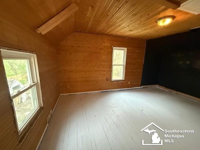 empty room with wood walls, wooden ceiling, and lofted ceiling