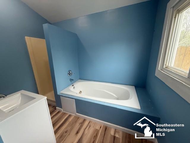 full bathroom featuring a garden tub and wood finished floors