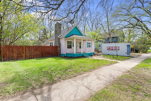 view of front of property featuring covered porch, fence, a chimney, and a front lawn