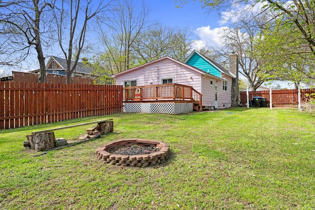 view of yard with a fenced backyard, a fire pit, and a deck