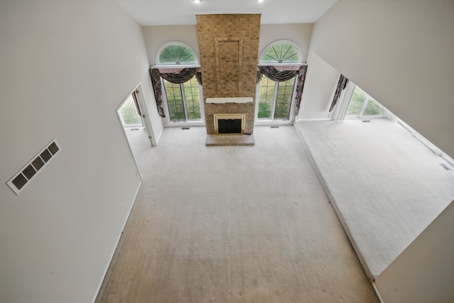 3351 Muerknoll Dr, Troy, MI 48084 - unfurnished living room with visible vents, carpet flooring, a towering ceiling, and a healthy amount of sunlight