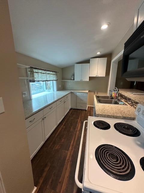 kitchen featuring white cabinets, dark wood-style flooring, black microwave, a sink, and electric stove