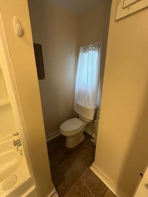 bathroom featuring tile patterned flooring, baseboards, a tub, and toilet