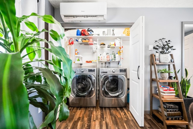 clothes washing area with washing machine and clothes dryer, laundry area, dark wood finished floors, and a wall unit AC