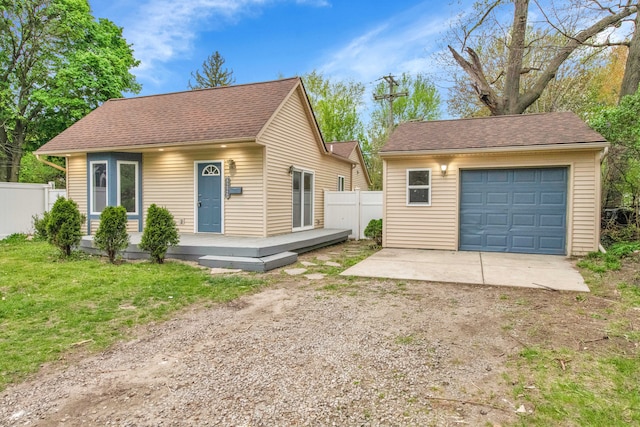 bungalow-style house with driveway, a deck, an outbuilding, a detached garage, and fence
