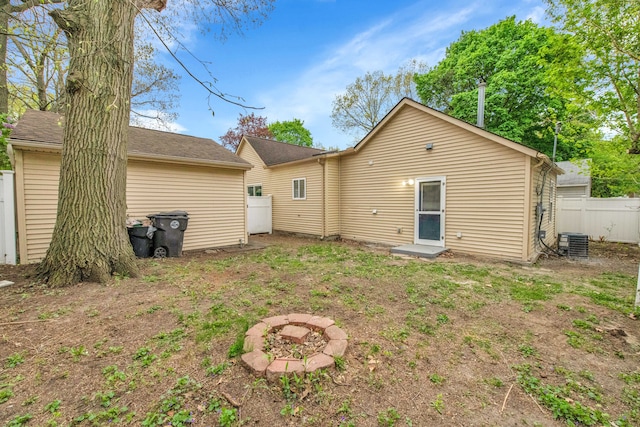 rear view of property featuring fence and central AC