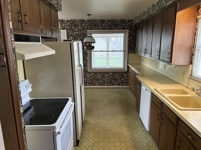 kitchen featuring white appliances, light floors, light countertops, a sink, and exhaust hood