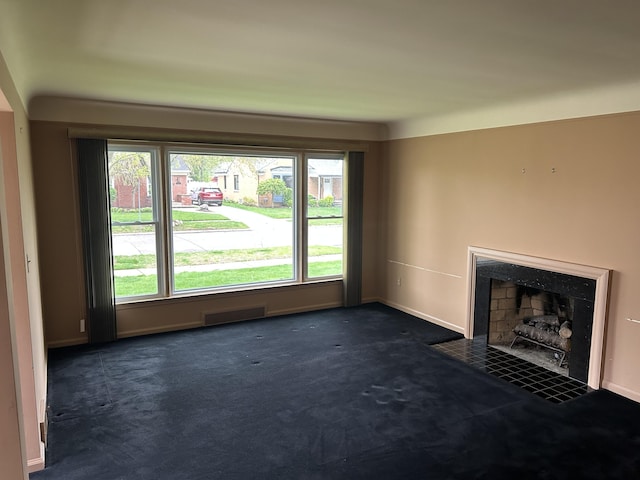 unfurnished living room with baseboards, a fireplace with flush hearth, and dark carpet