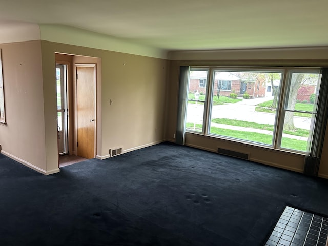 unfurnished room with baseboards, visible vents, and dark carpet