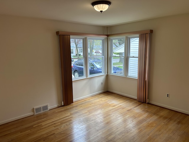 spare room featuring light wood-style floors, baseboards, and visible vents