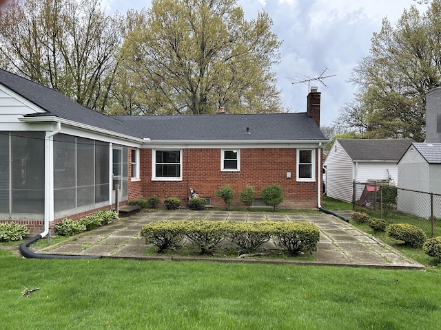 back of property featuring fence, brick siding, a chimney, a patio, and a yard