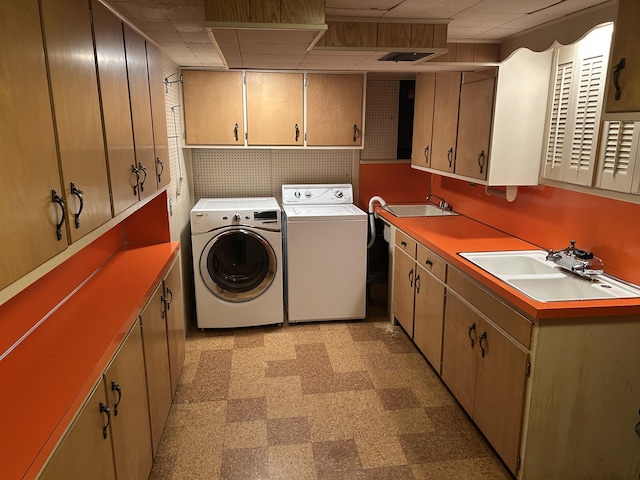 laundry room featuring a sink, light floors, cabinet space, and washer and clothes dryer