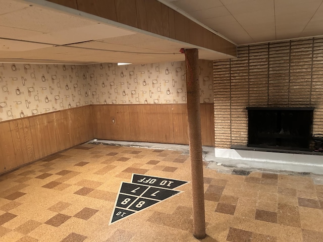 finished basement featuring a wainscoted wall, tile patterned floors, a fireplace, and wood walls