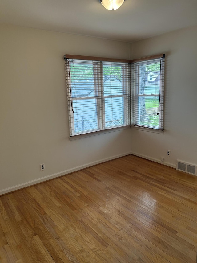unfurnished room featuring baseboards, plenty of natural light, light wood finished floors, and visible vents