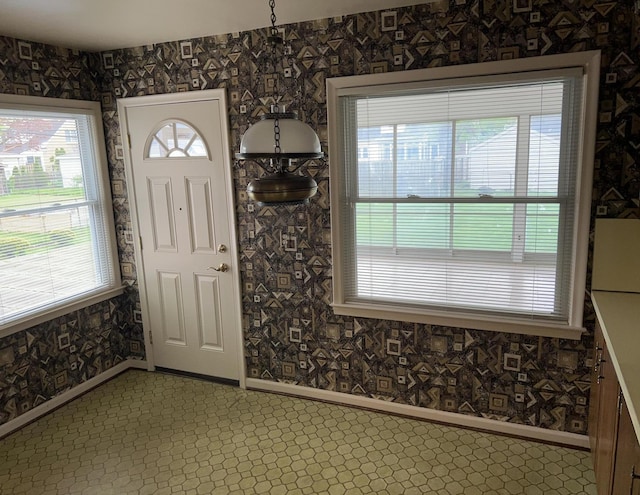 entryway featuring baseboards, wallpapered walls, and a healthy amount of sunlight