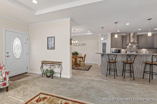 foyer entrance with baseboards, recessed lighting, a tray ceiling, and light carpet
