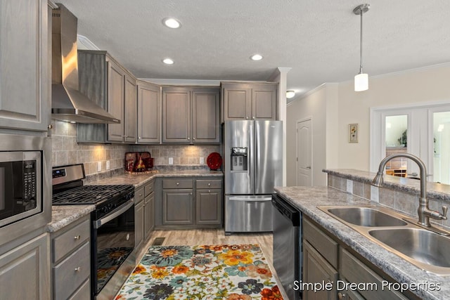 kitchen with ornamental molding, wall chimney exhaust hood, a textured ceiling, a sink, and stainless steel appliances