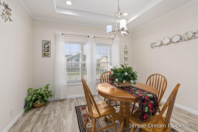 dining room featuring light wood-type flooring, baseboards, a tray ceiling, and a chandelier