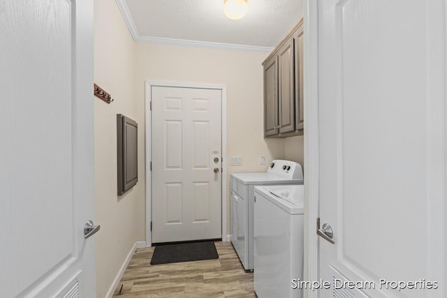 laundry room featuring cabinet space, crown molding, separate washer and dryer, light wood-style flooring, and baseboards