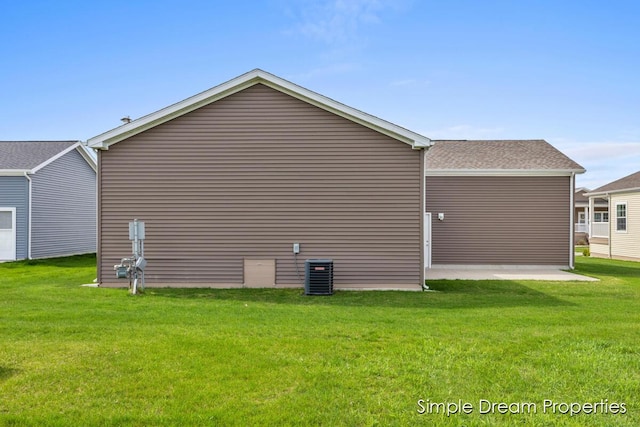 view of side of property featuring a yard, a patio area, and central AC