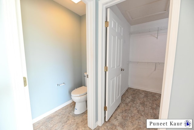 bathroom featuring baseboards, a spacious closet, and toilet