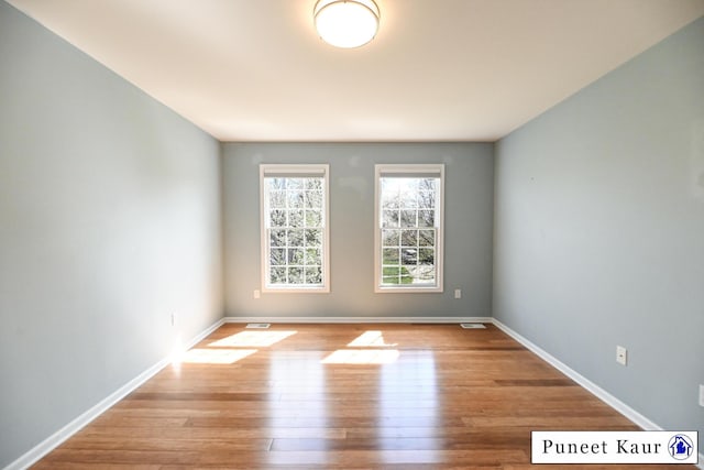 spare room with baseboards, visible vents, and wood finished floors