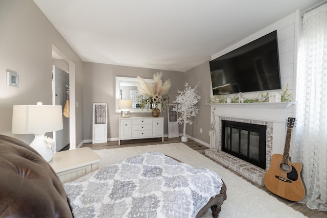 bedroom with a glass covered fireplace, baseboards, and wood finished floors