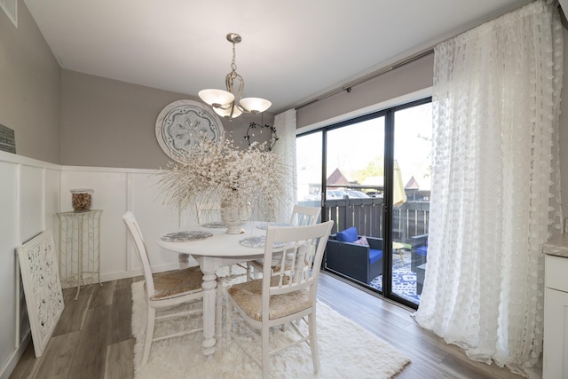 dining area featuring visible vents, wainscoting, wood finished floors, a notable chandelier, and a decorative wall