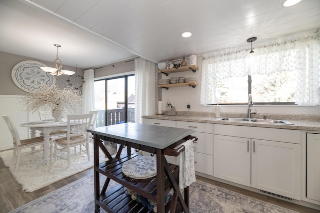 kitchen with hanging light fixtures, a notable chandelier, a sink, light countertops, and wood finished floors
