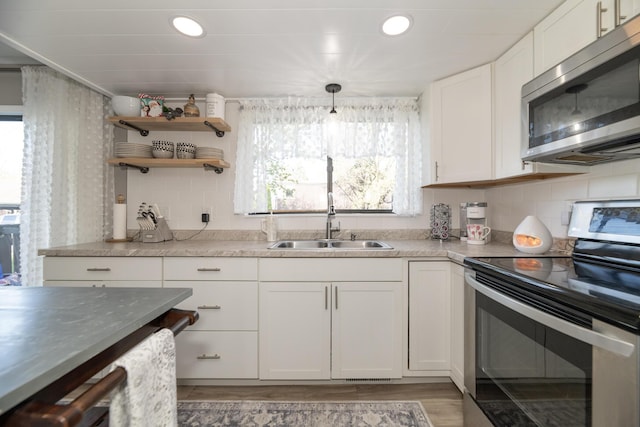 kitchen featuring decorative backsplash, plenty of natural light, stainless steel appliances, and white cabinets