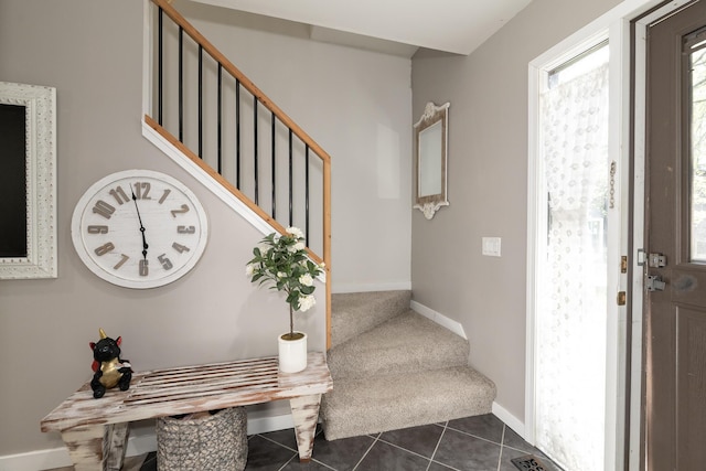 foyer entrance with baseboards, dark tile patterned floors, stairway, and dark colored carpet