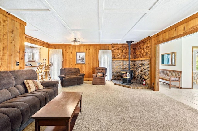 carpeted living area with a wood stove, tile patterned floors, and wood walls