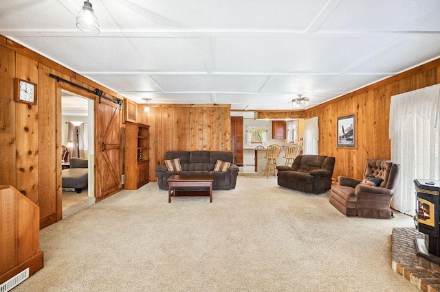living room featuring light colored carpet, a wood stove, and wood walls
