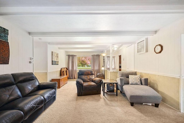 carpeted living room with beamed ceiling and wood walls