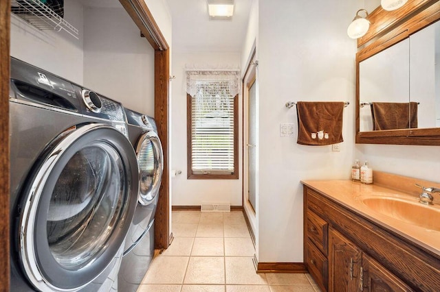 clothes washing area featuring laundry area, a sink, baseboards, and washer and dryer
