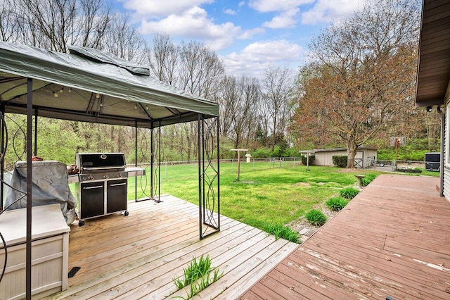wooden deck with grilling area, a lawn, an outbuilding, a gazebo, and fence
