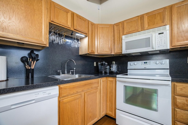 kitchen featuring a sink, decorative backsplash, dark countertops, and white appliances
