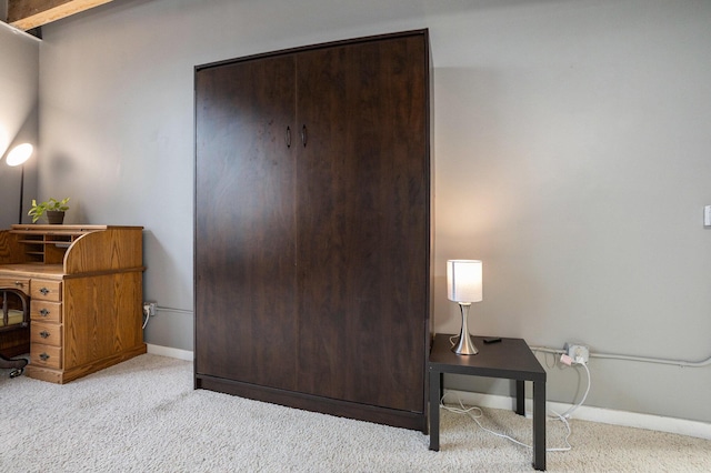 office area featuring baseboards and light carpet