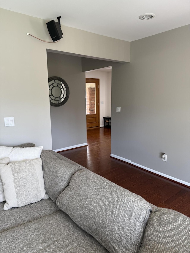 living area with baseboards and dark wood-type flooring