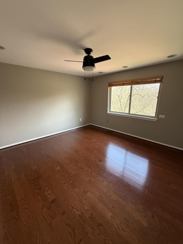 unfurnished room with dark wood-style flooring, baseboards, and a ceiling fan