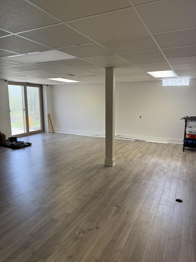 below grade area featuring baseboards, a drop ceiling, and wood finished floors