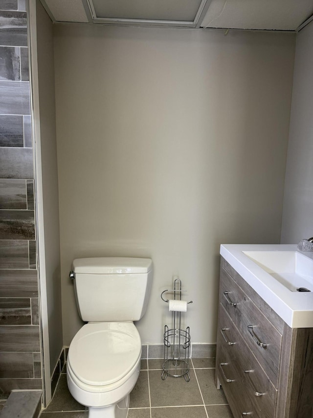 bathroom with baseboards, tile patterned floors, toilet, and vanity