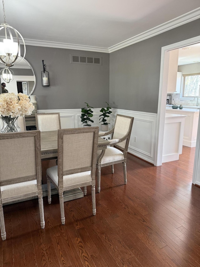 dining area featuring an inviting chandelier, crown molding, wainscoting, and visible vents